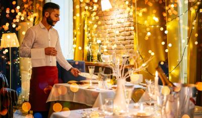 homem branco garçom em um restaurante com decorações natalinas - Assaí Atacadista - marketing sensorial