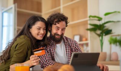 homem e mulher na frente de um notebook com um cartão de crédito nas mãos - Cartão Passaí - Assaí Atacadista