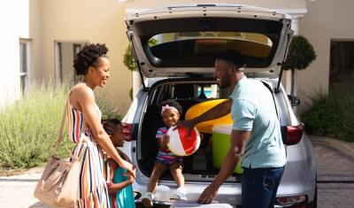 homem mulher e crianças negras felizes colocando malas em um carro-Assaí Atacadista-viagem bate e volta
