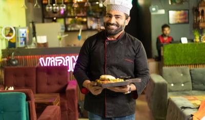 homem sorrindo segurando um prato de comida em um restaurante - Assaí Atacadista - Food Service