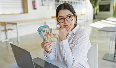 jovem brasileira com notas de dinheiro na mão - decisões financeiras - Assaí Atacadista