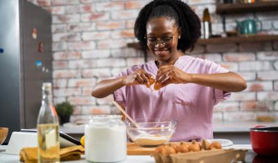 jovem negra feliz cozinhando - comércios transformadores - Assaí Atacadista