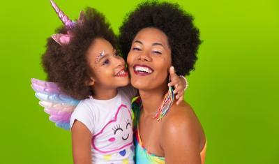 mãe e filha negras felizes com roupas e acessórios de carnaval em um fundo verde - carnaval com crianças - Assaí Atacadista