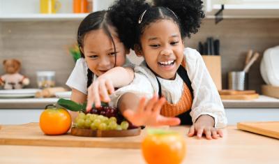 meninas crianças felizes na cozinha com frutas na mesa - frutas para crianças - Assaí Atacadista