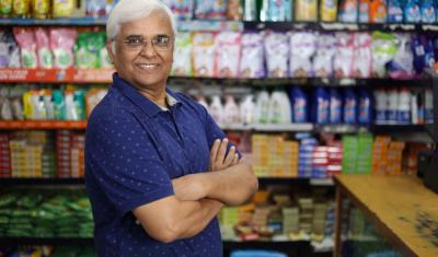 homem idoso com os braços cruzados em um comércio - Mês do Comerciante - Assaí Atacadista