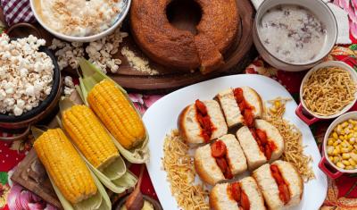 mesa com diferentes pratos como milho cozido bolo pipoca e mini cachorro quente-festas com saúde-Assaí Atacadista