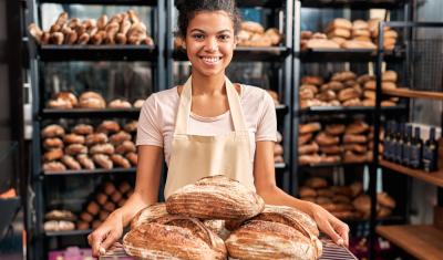 mulher negra em uma panificadora segurando pães - pão - Assaí Atacadista