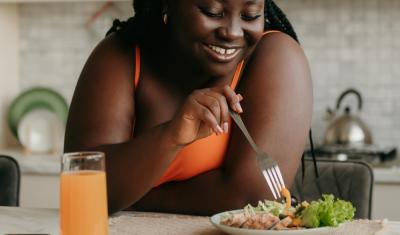 mulher negra feliz com um garfo olhando para um prato de comida - Assaí Atacadista - equilíbrio