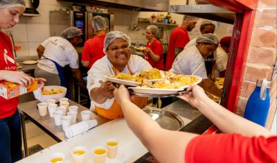 mulher negra feliz entregando um alimento para outra pessoa-Relatório Anual 2025-Instituto Assaí