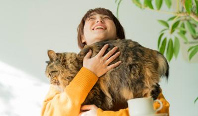 pessoa branca abraçando um gato grande - cafeteria pet - Assaí Atacadista