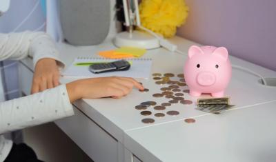 pessoa branca contando moedas em uma mesa com um cofre de porquinho rosa-voltas a economizar-Assaí Atacadista