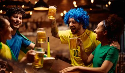 pessoas caracterizadas com as cores da bandeira do Brasil em um bar brindando-camarote vip-Assaí Atacadista