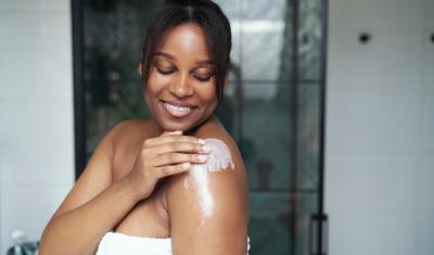  mulher negra sorrindo passando hidratante na pele-temporada de hidratação-Nivea-Assaí Atacadista