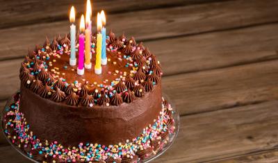 Bolo de aniversário sabor chocolate com velhas coloridas e granulados - Assaí Atacadista