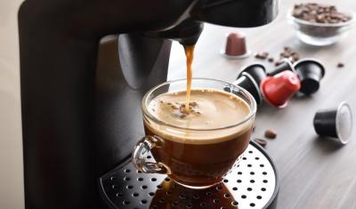 xícara com café em uma máquinha e cápsulas de café do lado-Assaí Atacadista-JDE