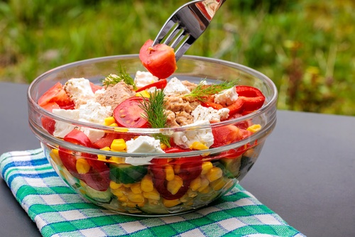 tigela transparente com uma salada de milho pepino tomate e outros ingredientes-receitas com milho-Assaí Atacadista