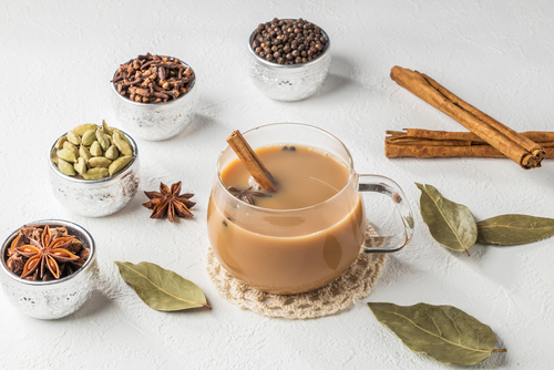 xícara transparente com chai latte e especiarias do lado - receitas de chás - Assaí Atacadista